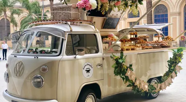 Un furgone vintage allestito per un aperitivo fuori chiesa matrimonio, con fiori e dolci.
