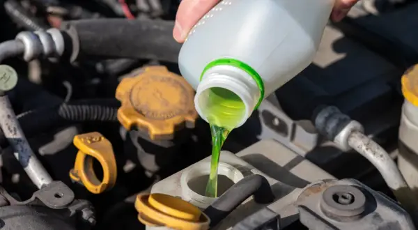 Main verte versée dans le réservoir, assurant le bon niveau liquide de refroidissement du moteur.