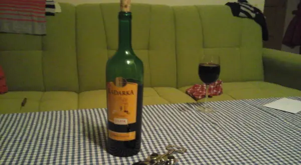 Butelka Kadarka na stole, obok kieliszek z winem. Zastanawiam się, kadarka ile procent ma w sobie?