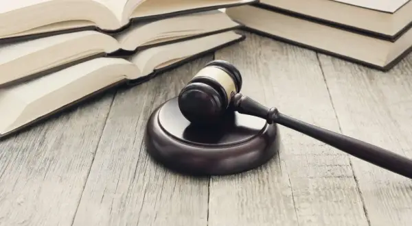 Młotek sędziowski i otwarte księgi na drewnianym stole. Dowiedz się, jak napisać apelację od wyroku o alimenty.