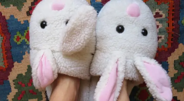 Pantofole a forma di coniglio bianco con orecchie rosa, pronte per essere lavate in lavatrice.