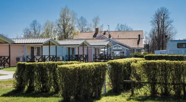 Färgglada stugor och reception vid Villa Björkhagen, Jönköping. En husbil syns till höger.