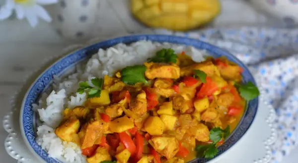 Pyszny kurczak z mango po tajsku, podany z ryżem. Aromatyczne kawałki kurczaka, słodkie mango i papryka w złocistym sosie curry.