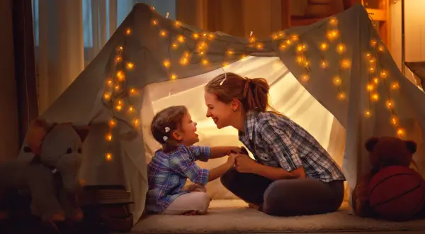 Mama i córka w namiocie z lampek, śpiewają piosenki o mamie.