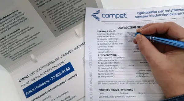 Dłoń z długopisem wypełniająca formularz oświadczenia sprawcy kolizji drogowej.