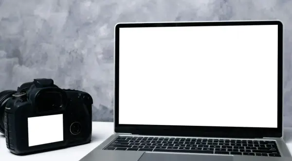 Aparat cyfrowy i laptop obok siebie. Idealne do nauki, jak przenieść zdjęcia z aparatu cyfrowego na telefon.