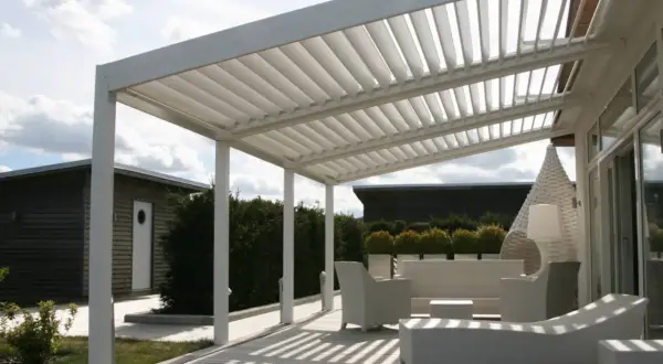 Un moderno porche patio de casa con muebles blancos de mimbre y una pérgola de listones.