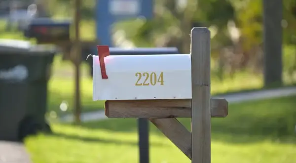 A white mailbox with the number 2204, mounted on a wooden post, ready for mail delivery. This image could be a visual guide on how to install a mailbox.