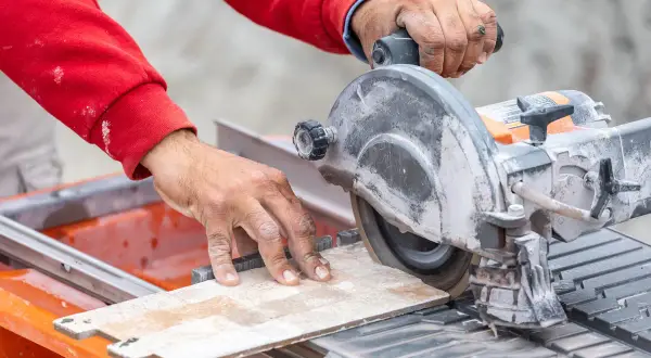 Mani esperte guidano una sega circolare per un preciso **taglio gres porcellanato**.