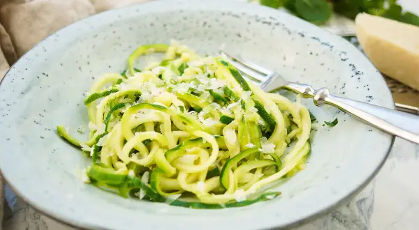 Ein Teller mit Zoodles, einem leichten Zucchini-Nudel-Gericht, bestreut mit Parmesan. Ein einfaches und gesundes Zoodles Rezept.