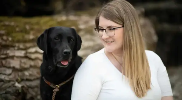 Ein schwarzer Labrador und eine Frau mit Brille lächeln. Perfekt für eine vorlage trainingsplan hund.