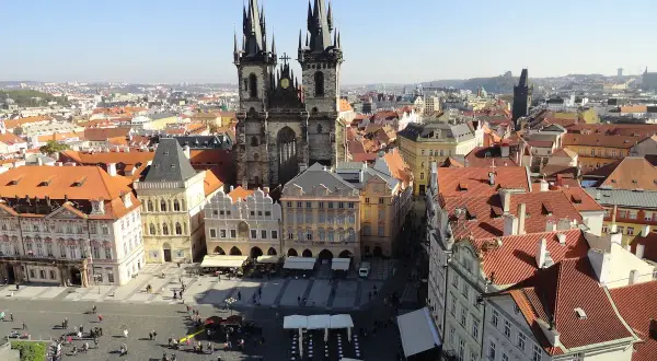 Blick über die Dächer der **Prag Stadt** mit der Teynkirche im Zentrum. Menschen beleben den Platz.