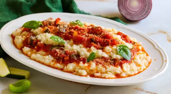 Frascarelli ricetta originale: un piatto cremoso con sugo di pomodoro, verdure e parmigiano, guarnito con basilico fresco.