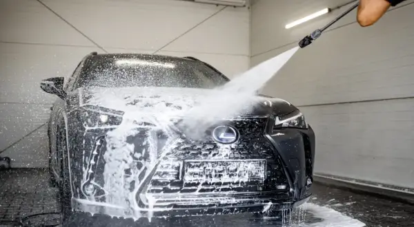 Czarny Lexus w myjni bezdotykowej. Woda i piana spływają po masce i grillu. Poznaj myjnia bezdotykowa triki, by Twój samochód lśnił!