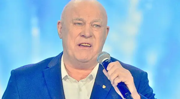 Łysy mężczyzna w garniturze trzyma mikrofon. Słychać jego głos: "Vox szczęśliwej drogi już czas!".