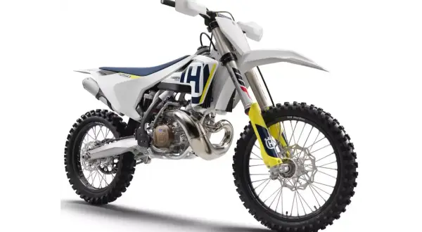 Nowy motocykl cross Husqvarna 250 gotowy na wyzwania toru. Biało-niebiesko-żółte malowanie, potężny silnik i terenowe opony.