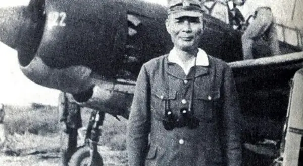 En japansk kamikaze pilot står framför ett flygplan.
