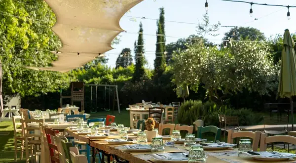 Tavoli apparecchiati all'aperto in un giardino lussureggiante, un'atmosfera perfetta per scoprire i migliori ristoranti a Firenze.