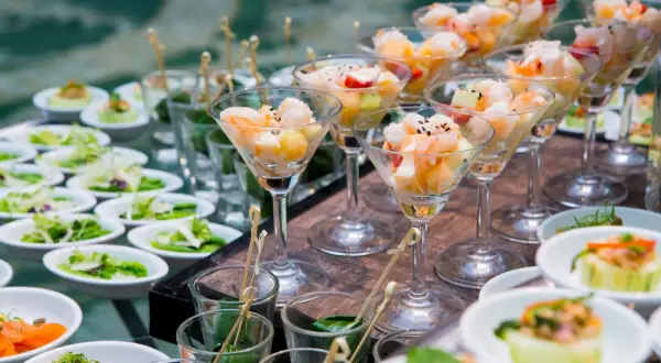 Eleganckie menu na wesele: krewetki z owocami w kieliszkach, sałatki i przystawki w małych miseczkach.