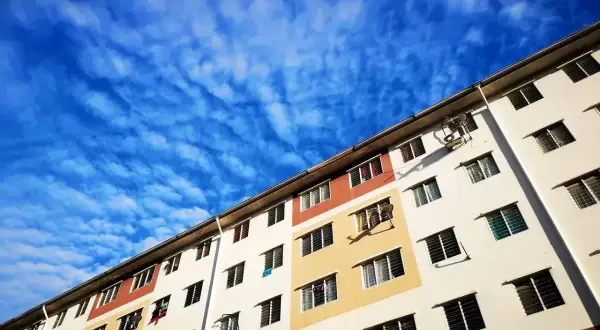 Wielopiętrowy budynek mieszkalny, typowe mieszkanie socjalne, pod błękitnym, pofalowanym niebem.