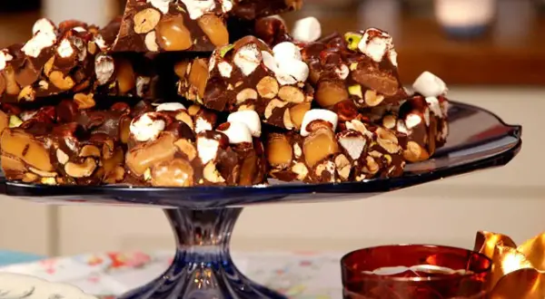 En hög med chokladbitar med nötter, karamell och marshmallows. En härlig rocky road-frestelse på ett blått fat.