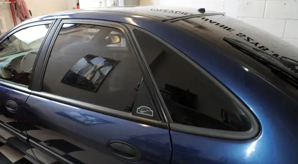 Ciemnoniebieski samochód z przyciemnianiem szyb 30 procent. Widać odbicie wnętrza w przyciemnionych szybach.