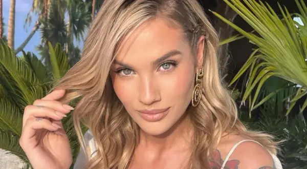 Karolina Gilon z burzą blond włosów i tatuażami na ramieniu, otoczona palmami. Ciekawe, ile lat ma Karolina Gilon?