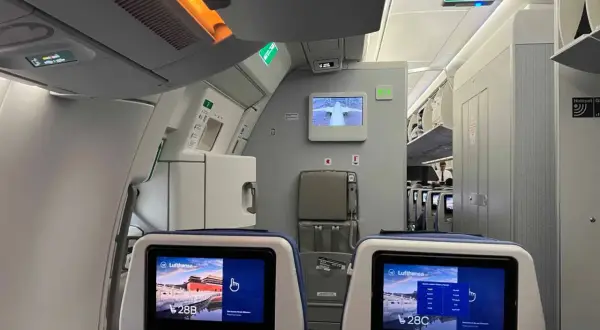 Blick in ein Flugzeug, wo man bequem sitzen kann. Die Bildschirme zeigen die Sitzplätze 28B und 28C.