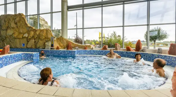 Ludzie relaksują się w jacuzzi. Szukając, które termy są najtańsze, warto sprawdzić oferty z podobnymi atrakcjami.