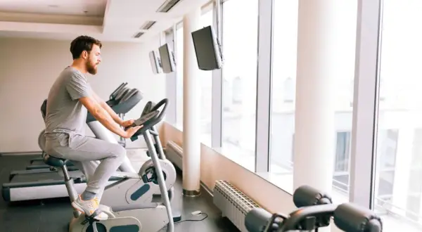 Mężczyzna ćwiczy na rowerze stacjonarnym, który może być dobrym wyborem, jeśli zastanawiasz się, jaki rower stacjonarny do rehabilitacji kolana wybrać.