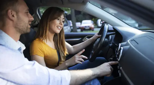 Un jeune couple discute en voiture. Elle conduit, il lui montre quelque chose sur le tableau de bord. La conduite accompagnée 3000 km en combien de temps ?