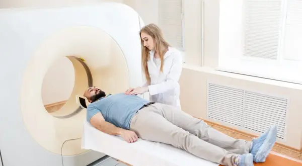 Pacjent leży na stole do rezonansu magnetycznego, pielęgniarka przygotowuje go do badania. Zastanawiasz się, ile się czeka na wynik rezonansu z kontrastem?