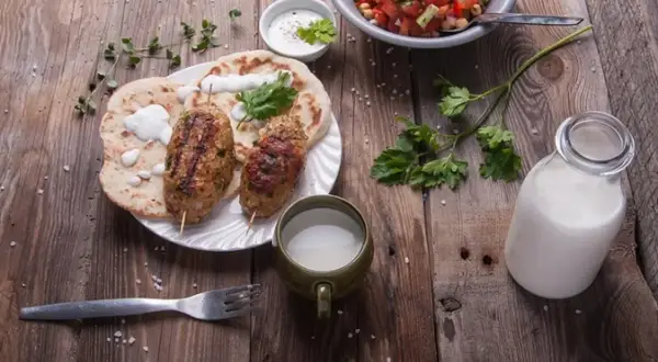 Kebab z płaskim chlebem, sałatką i napojem. Czy to ayran? To orzeźwiający napój jogurtowy, idealny do takiego posiłku.
