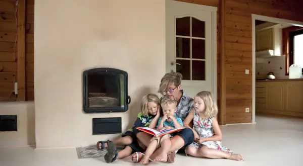 Een moeder leest voor aan haar drie kinderen bij de open haard. Een moment van rust en samenzijn, ontspullen voor en na een drukke dag.