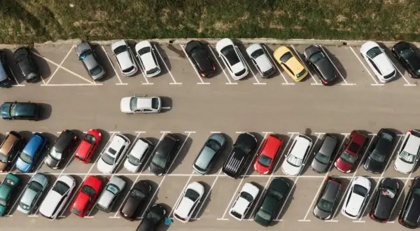 Widok z góry na parking z samochodami. Widać jak prawidłowo wykonać parkowanie skośne kiedy skręcać.