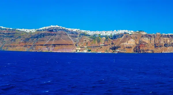 Widok na białe miasteczko na klifie nad błękitnym morzem na Santorini.