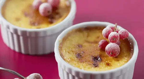 Deux flans aux œufs, dorés et caramélisés, ornés de groseilles givrées. Un délice visuel et gustatif.