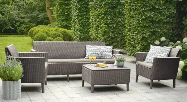 Relaks na tarasie w stylu boho: wygodna sofa, fotele, stolik kawowy z przekąskami i napojami, otoczone zielenią.