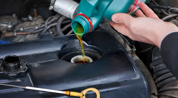 Persona vierte aceite nuevo en el motor. El estado del vehículo influye en su longevidad.