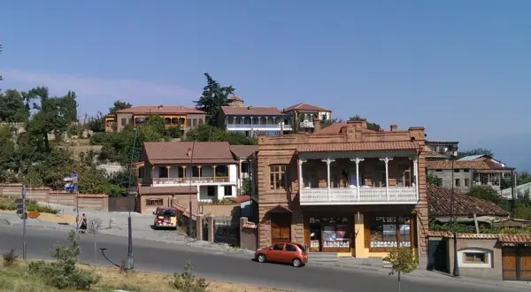 Urokliwe uliczki Telavi, Gruzja, z tradycyjną architekturą i balkonami. Pomarańczowy samochód jedzie po drodze.