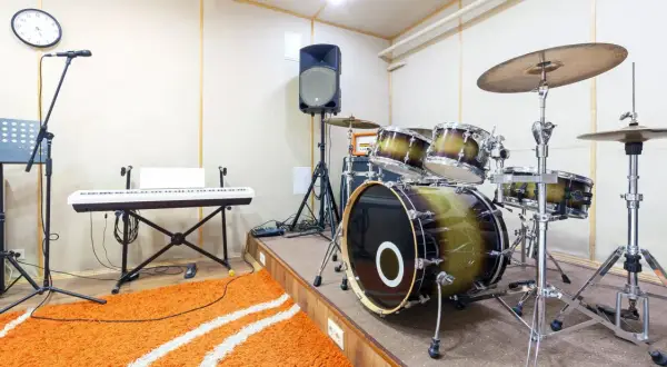 Ein Schlagzeug mit einem großen Bass-Instrument, Keyboard, Mikrofon und Lautsprecher in einem Aufnahmestudio.