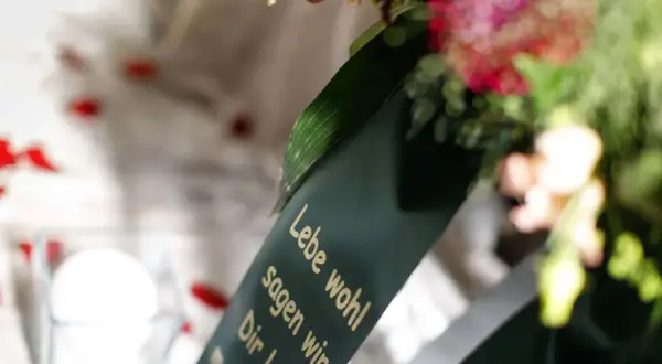 Trauerkranz mit Spruch "Lebe wohl". Mögliche Nachteile beim Kirchenaustritt für die Beerdigung.