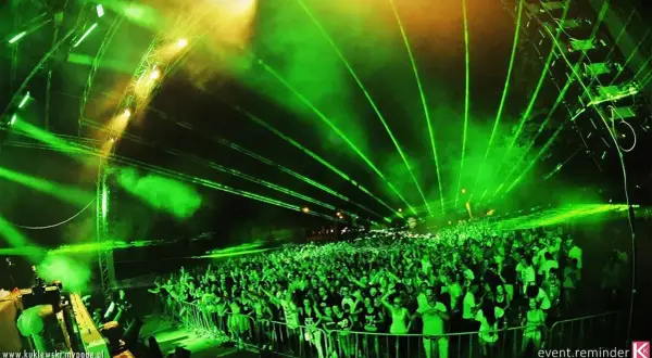 Tłum ludzi na festiwalu **Audiolake** pod zielonymi laserami i światłami.