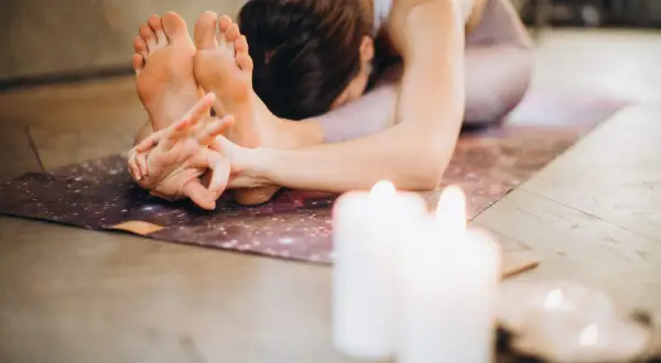 Una mujer en postura de yoga, con las manos entrelazadas en los pies. La práctica de **sadhana** es un camino de autoconocimiento.