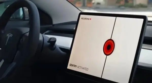 Teslas mittskärm visar "SENTRY ACTIVATED" med en röd ögonliknande ikon. Bilen är redo att agera som en vaktpost.