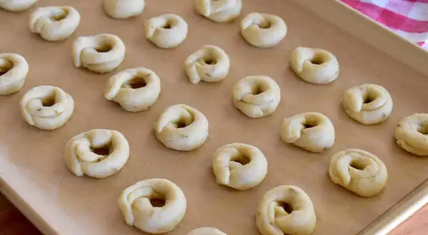 Små, ringformade taralli ligger redo på en bakplåt. Ett perfekt taralli recept för hembakade godsaker.