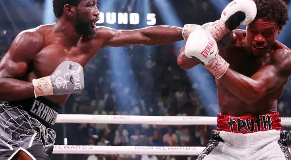 Terence Crawford lands a punch wearing grey Everlast gloves. His opponent, wearing white Everlast gloves, attempts to block.