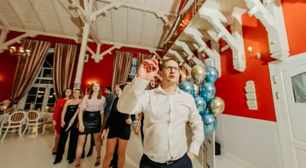 Ludzie tańczą na imprezie firmowej. W tle balony i dekoracje, świetne pomysły na jubileusz firmy.