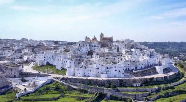 Panoramica di uno dei borghi medievali in Puglia, con case bianche a picco sul mare e un cielo azzurro.