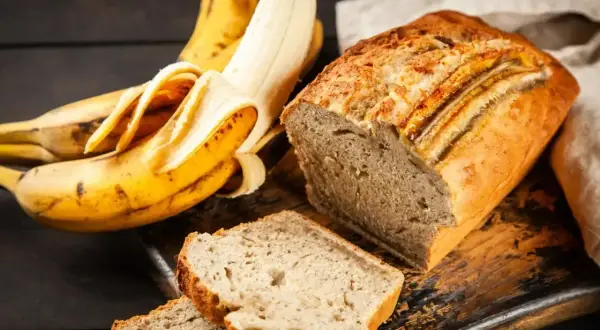 Wilgotne ciasto bananowe, obok dojrzałych bananów, kusi apetycznym wyglądem. Idealne na deser lub śniadanie.